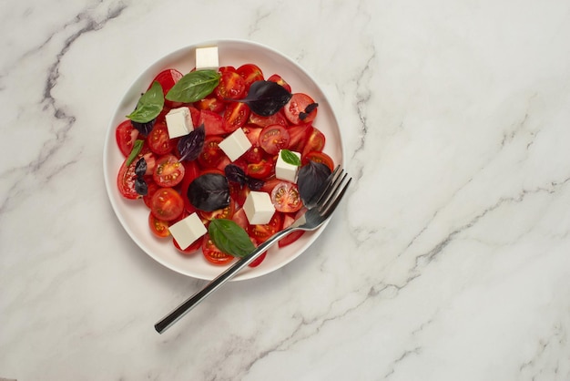 Salat mit Tomaten, Feta und Basilikum auf grauem Hintergrund