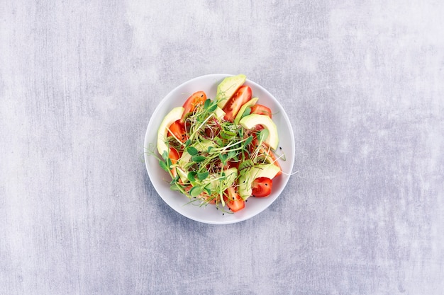 Salat mit Tomaten, Ovacado und Mikrogrün auf einem grauen Tisch