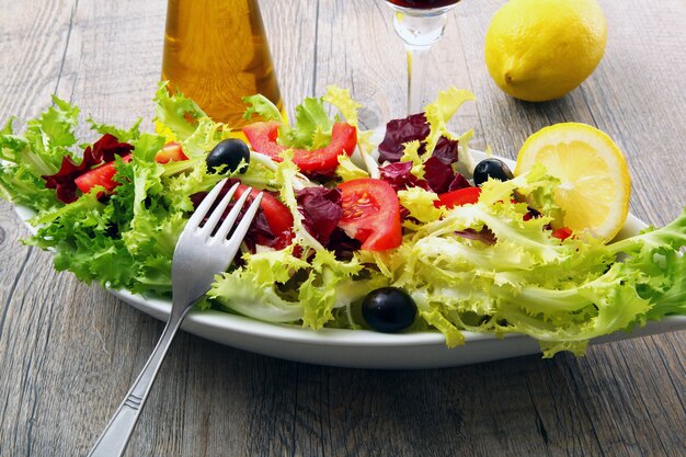 Salat mit Tomaten und Oliven auf Holztisch