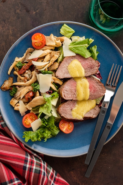 Salat mit warmem Rindfleisch mit Austernpilzen, Tomaten und Gemüse. Ansicht von oben