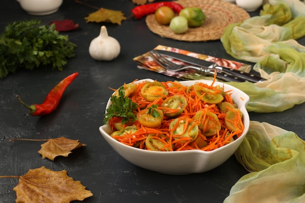 Salat nach koreanischer Art mit grünen Tomaten und Karotten in einer weißen Salatschüssel