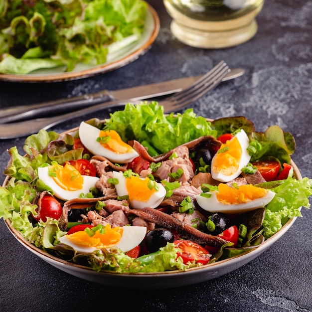 Salat Nicoise mit Thunfisch, Eiern, grünen Bohnen, Tomaten, Oliven, Salat und Sardellen