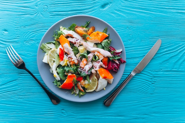 Salat und Nudeln mit Meeresfrüchten auf blauem Hintergrund