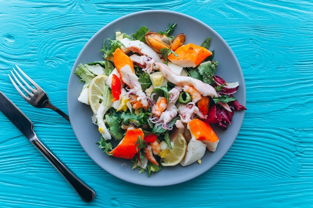 Salat und Nudeln mit Meeresfrüchten auf blauem Hintergrund