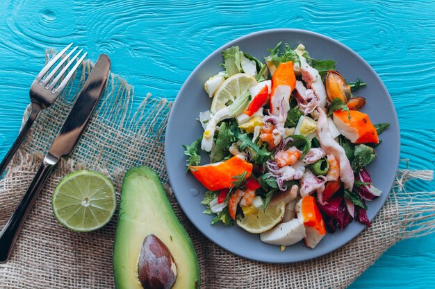 Salat und Nudeln mit Meeresfrüchten auf blauem Hintergrund