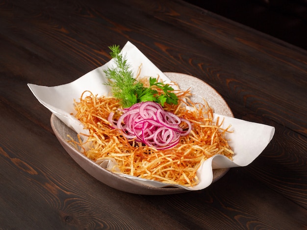 Foto salat von pommes frites, roten zwiebeln und frischem gemüse in einer schüssel auf einem hintergrund von hölzernen verlassenen brettern