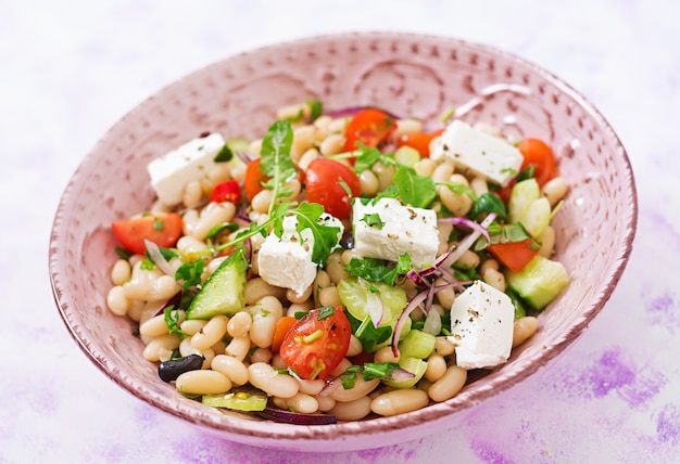 Salat von weißen Bohnen, von Tomate, von Sellerie, von Gurke, von Arugula, von roter Zwiebel und von Feta in der Schüssel