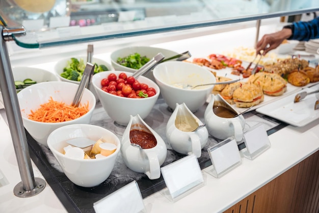 Salatbar mit verschiedenen Saucen, Gemüse und Brot auf dem Buffettisch