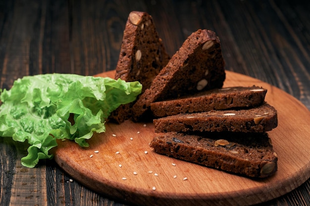 Salatblätter und Roggenbrot mit Pinienkernen auf einem Holzbrett