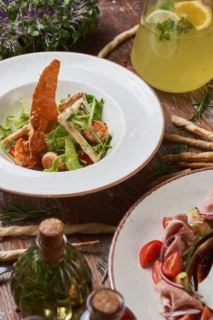 Salate mit gekochtem Schweinefleisch und Garnelen auf einem Holztisch mit Saucen