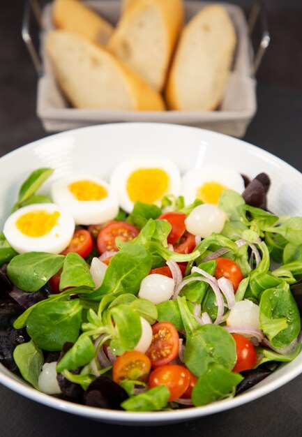 Salateier gemischt mit süßen Tomaten, eingelegtem Knoblauch, Zwiebeln und Spinat sind eine gesunde Ernährung für jede Mahlzeit.