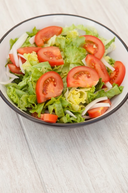 Salatschüssel auf einem weißen hölzernen Hintergrund