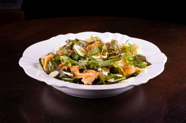 Salatteller mit Gurke und Lachs auf Holztisch gesunde Ernährung mit Fisch