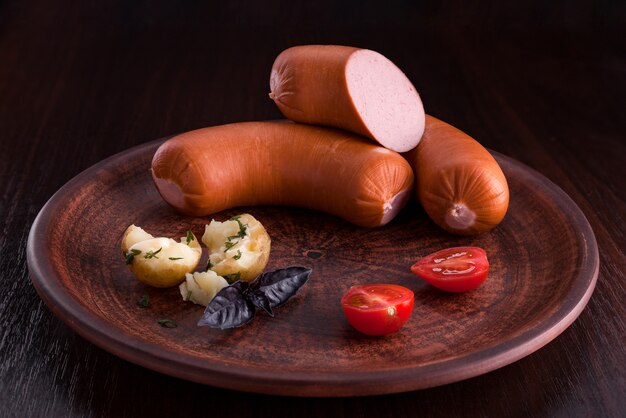 Salchicha con aperitivos en un plato y en una tabla de cortar.