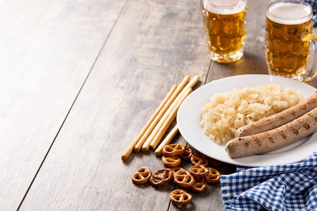 Salchicha Bratwurst, chucrut, pretzels y cerveza en la mesa de madera