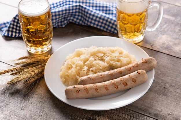 Salchicha Bratwurst, chucrut, pretzels y cerveza en la mesa de madera