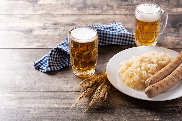 Salchicha Bratwurst, chucrut, pretzels y cerveza en la mesa de madera