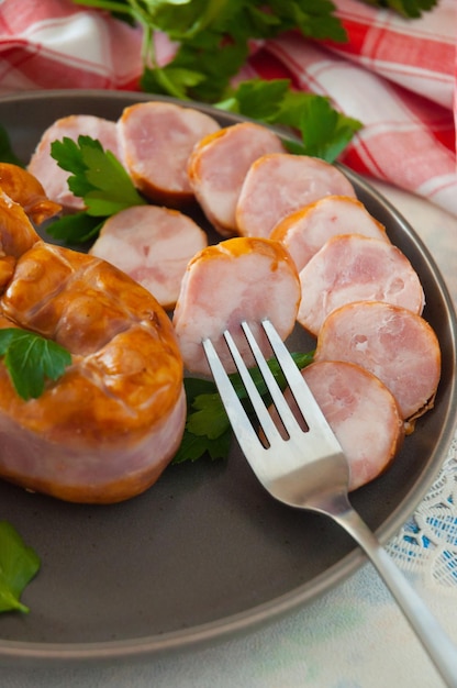 Salchicha de cerdo casera en rodajas hervida y ahumada en un plato gris