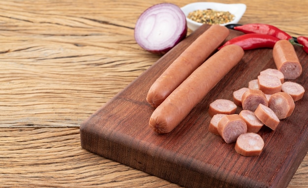 Salchicha de cerdo fina sobre tabla de madera con condimentos y copie el espacio.