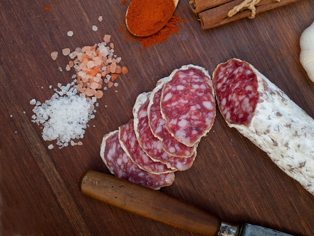 Salchicha curada de salame italiano tradicional cortada en una tabla de madera