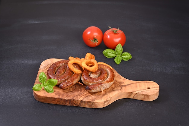 Salchicha en espiral picante asada con hojas de albahaca y patatas fritas