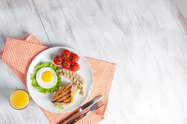 Salchicha frita con huevos y verduras en una sartén.