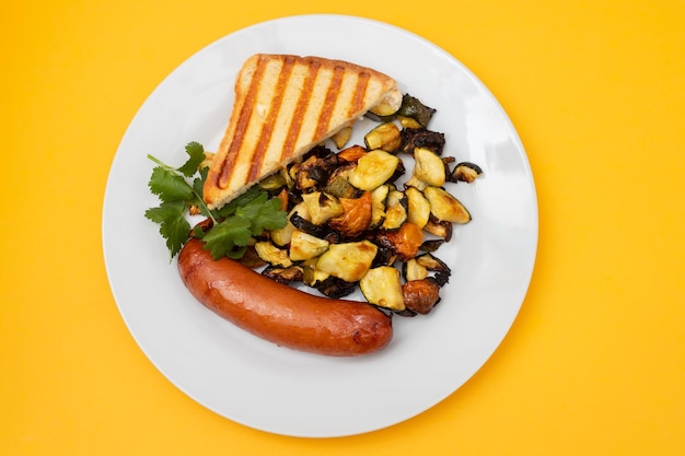 Salchicha frita con verduras y tostadas en plato