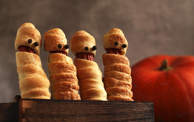 Salchicha en la masa en forma de momia en una caja de madera para la fiesta de Halloween