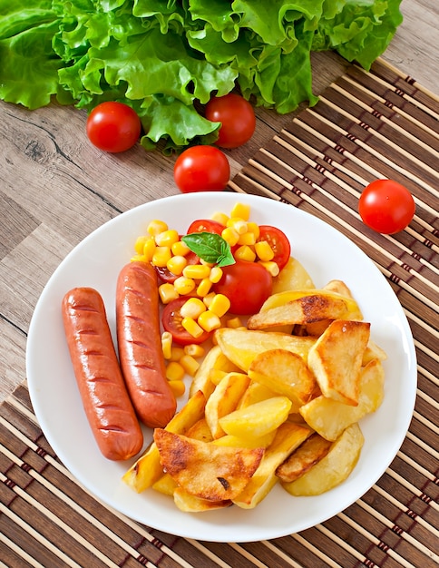 Foto salchicha con papas fritas y verduras en un plato