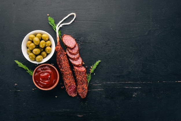 Foto salchicha paperoni salami con pimentón sobre un fondo de madera negra vista superior espacio libre para el texto