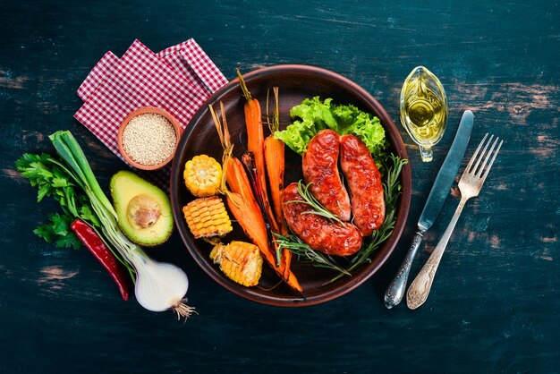 Salchicha a la parrilla Maíz y zanahorias al horno Sobre un fondo de madera Vista superior Espacio de copia