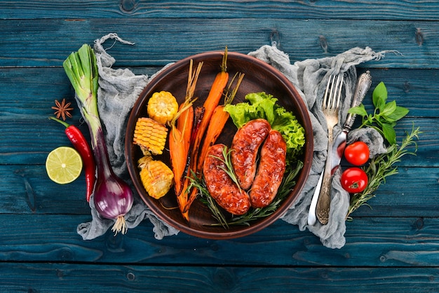 Salchicha a la parrilla maíz y zanahorias al horno sobre un fondo de madera vista superior espacio de copia