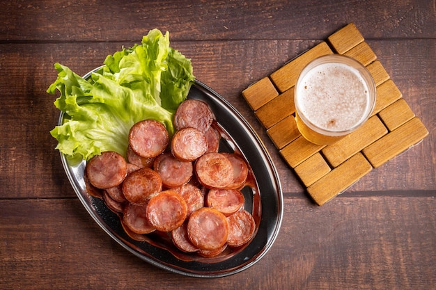 Salchicha de pepperoni frita en rodajas con un vaso de cerveza en la mesa