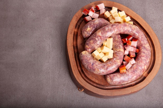 Salchicha de queso artesanal de charcutería con tocino y cerdo bajo la vista superior del tablero de madera