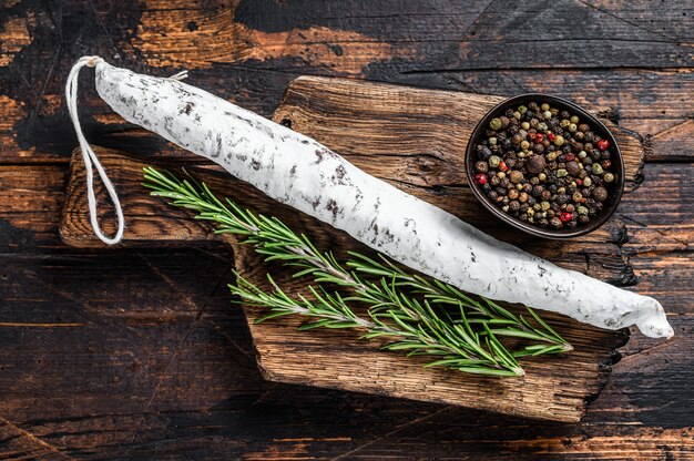 Foto salchicha de salami fuet español sobre una tabla de cortar de madera.