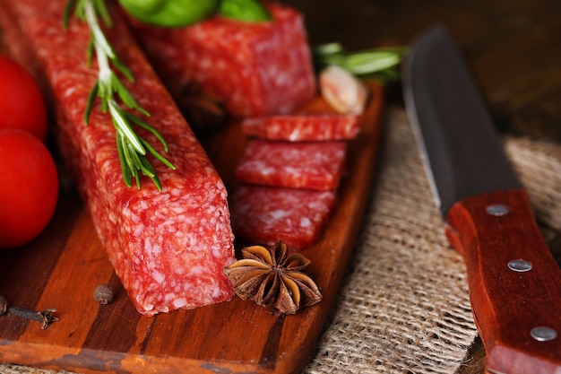 Salchicha salami sabroso y especias sobre fondo de madera