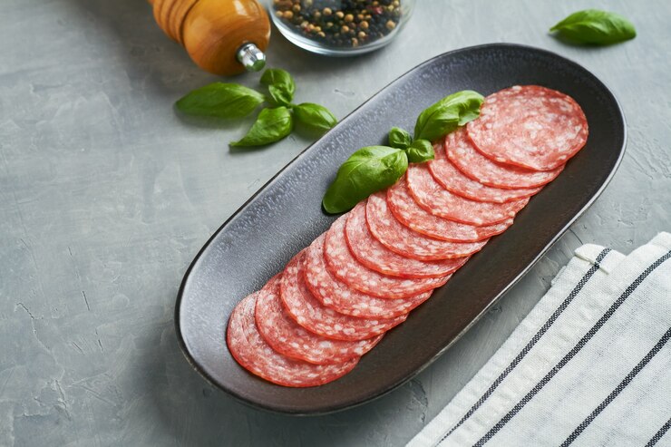 Salchicha de salami sobre fondo gris placa negra