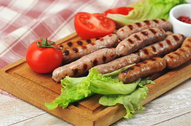 Salchichas ahumadas a la parrilla, hojas de lechuga, tomates