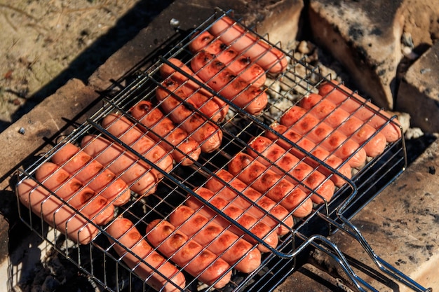 Salchichas asadas a la parrilla en barbacoa cocinando en fogata