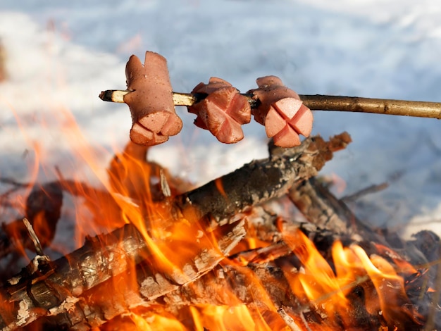 Salchichas de barbacoa checas tradicionales en un palo asado en la fogata Salchichas en la rejilla del palo