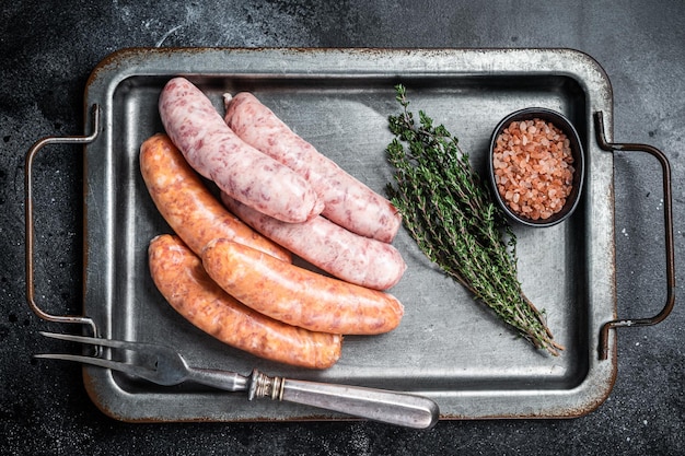 Salchichas de barbacoa crudas con especias en la bandeja de la cocina Fondo negro Vista superior