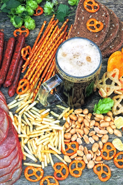 Salchichas bávaras, jamón, lúpulo, cerveza, aperitivos. Composición Oktoberfest con un vaso de cerveza oscura y aperitivos de cerveza. Pretzels, cerveza, lúpulo.