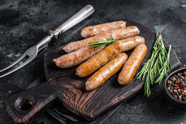 Salchichas Bratwurst o Hot Dogs fritos en una tabla de madera. Fondo negro. Vista superior.