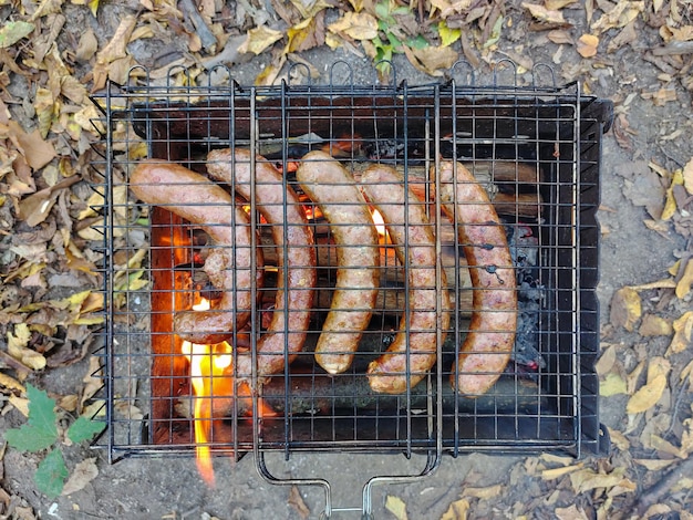 Las salchichas de carne se fríen en la parrilla Debajo de las hojas de la barbacoa Vista desde arriba