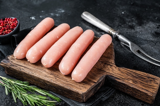 Salchichas de carne de pavo y pollo crudo fresco sobre una tabla de madera con romero