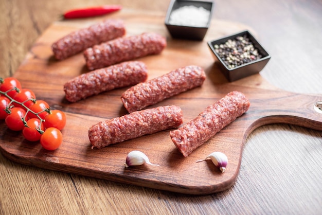 Salchichas caseras de lula kebab de carne cruda en una tabla de cortar. fondo de madera