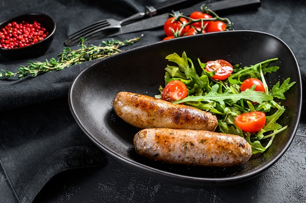 Salchichas de cerdo a la parrilla con ensalada de tomate y rúcula