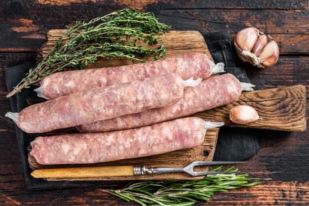 Salchichas crudas Bockwurst con carne de cerdo en una tabla de madera. Fondo de madera oscura. Vista superior.