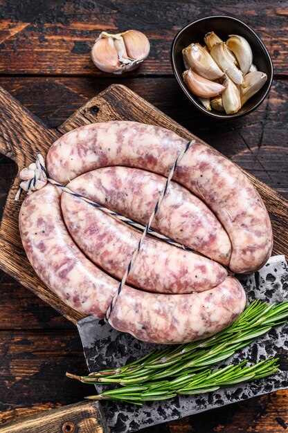 Salchichas crudas de carne de cerdo y ternera en la tabla de cortar de madera