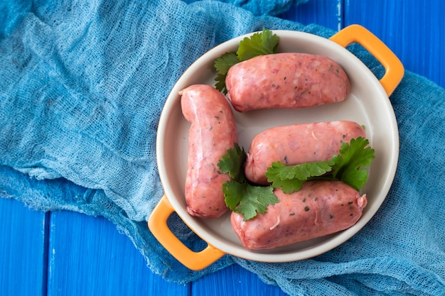 Salchichas crudas en plato sobre fondo de cerámica